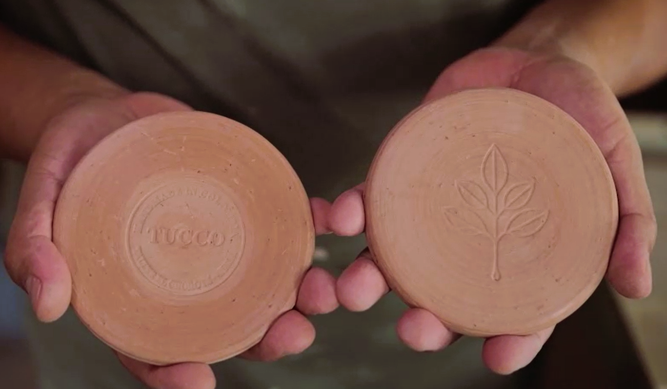 Colombian artisan hands holding handmade clay coasters crafted in Huila for Tucco corporate gifts.